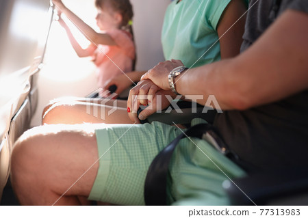Man and woman hold each other hands tightly in seats of planes 77313983
