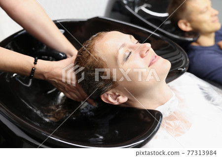 Woman in beauty salon wash her hair in sink 77313984