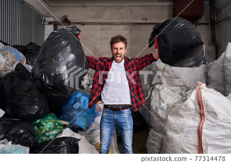 Man holding two heavy bags of rubbish 77314478