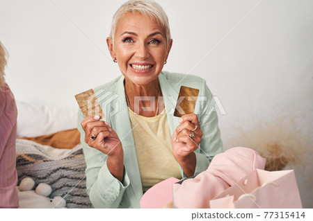 Woman holding two golden cards 77315414