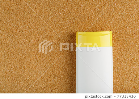 Sunscreen in a white bottle with a yellow cap on the golden sand. Sunscreen in a white bottle with a yellow cap on the golden sand. 77315430