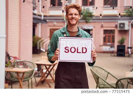 Barista holding showing sold chalkboard 77315475