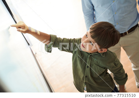 Inquisitive brunette caucasian boy showing at something at whiteboard Inquisitive brunette caucasian boy showing at something at whiteboard 77315510