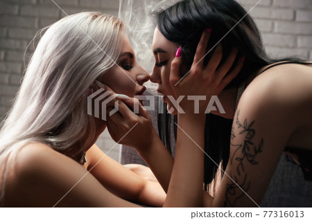 two young women inhale smoke on each other's lips while kissing showing the closeness of an LGBT relationship two young women inhale smoke on each other's lips while kissing showing the closeness of an LGBT relationship 77316013