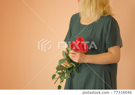 Portrait of young woman dressed in green dress holding bouquet of roses Portrait of young woman dressed in green dress holding bouquet of roses 77316046