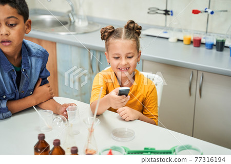 Cute smiling caucasian girl holding chemistry gadget in her hands 77316194