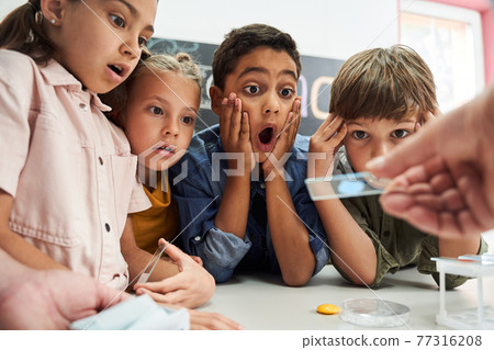 Open-eyed kids looking at the test glass that teacher holding Open-eyed kids looking at the test glass that teacher holding 77316208
