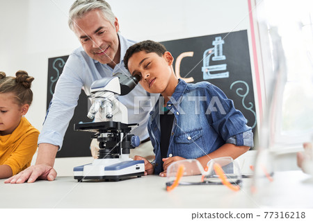 Handsome grey haired teacher looking satisfied to the boy 77316218