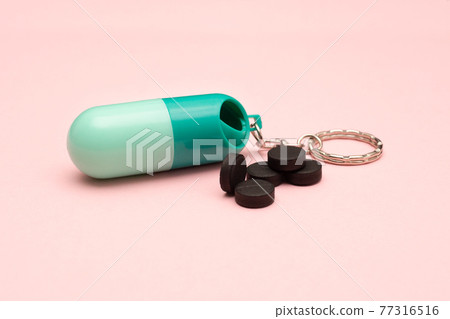 Travel pill box. Pill shape. The use of tablets in doses. Keep your health. Activated carbon on a colored background. 77316516