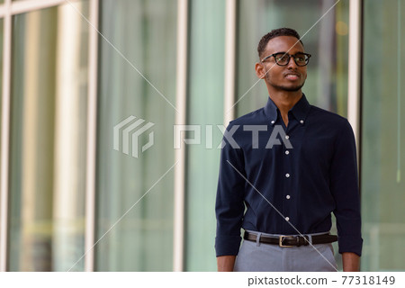 Portrait of handsome African businessman outdoors in city smiling and thinking Portrait of handsome African businessman outdoors in city smiling and thinking 77318149