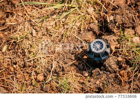 Sprinkler head in soil with copyspace. Newly installed irrigation system in backyard. 77318606