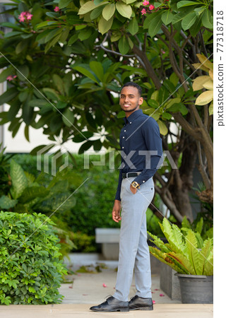 Full length shot of handsome African businessman outdoors at rooftop garden smiling Full length shot of handsome African businessman outdoors at rooftop garden smiling 77318718