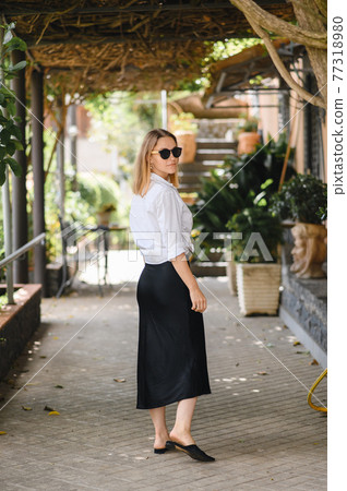 girl in sunglasses walks on European streets 77318980