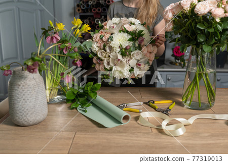 Handsome fresh bouquet. Flowers delivery. Woman florist create flower arrangement in a wicker basket. Beautiful bouquet of mixed flowers. Floral shop concept . Handsome fresh bouquet. Flowers delivery. Woman florist create flower arrangement in a wicker basket. Beautiful bouquet of mixed flowers. Floral shop concept . 77319013