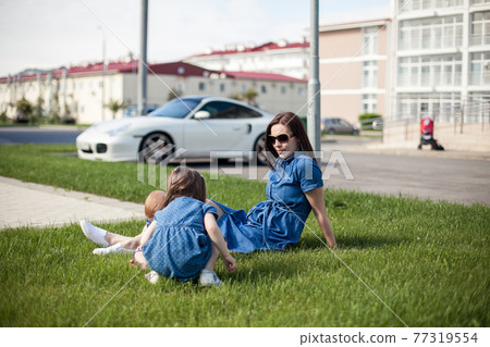 young mother with daughters dressed in denim dresses. Family look. Happy family young mother with daughters dressed in denim dresses. Family look. Happy family 77319554