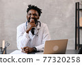 close-up portrait of black doctor smiling and looking at camera 77320258