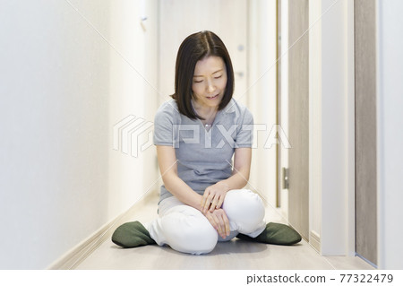 Tired, middle-aged woman sitting in the hallway Tired, middle-aged woman sitting in the hallway 77322479