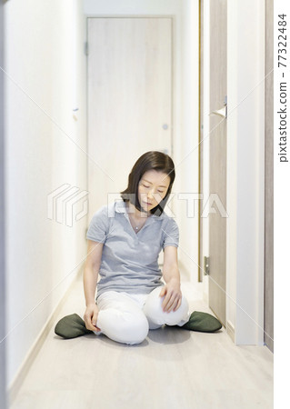 Tired, middle-aged woman sitting in the hallway Tired, middle-aged woman sitting in the hallway 77322484