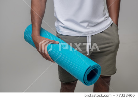 Male hand holding light blue sports mat Male hand holding light blue sports mat 77328400