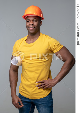 Smiling man in yellow tshirt and protective helmet Smiling man in yellow tshirt and protective helmet 77328417