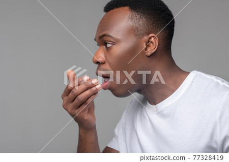 Close up of mans face with palm near mouth 77328419