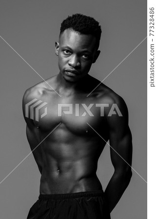Handsome shirtless muscular African man lookig at camera, black and white studio shot Handsome shirtless muscular African man lookig at camera, black and white studio shot 77328486