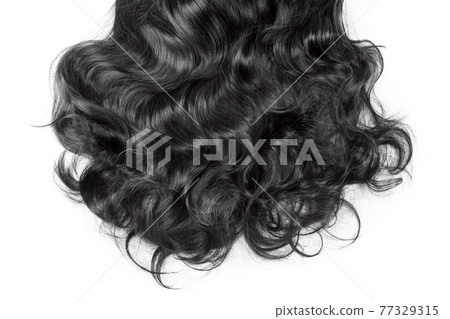 Black hair texture. Wavy long curly dark hair close up isolated on white. Hair extensions, materials and cosmetics, hair care, wig. Hairstyle, haircut or dying in salon 77329315
