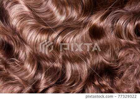 Brown hair texture. Wavy long curly light brown hair close up as background. Hair extensions, materials and cosmetics, hair care. Hairstyle, haircut or dying in salon. Brown hair texture. Wavy long curly light brown hair close up as background. Hair extensions, materials and cosmetics, hair care. Hairstyle, haircut or dying in salon. 77329322