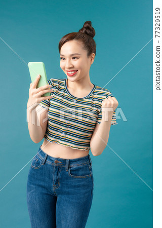 happy joyful girl holding mobile phone and celebrating a win 77329519