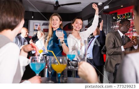 Young women enjoying corporate party Young women enjoying corporate party 77329923