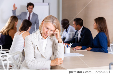 Frustrated mature woman on background with boss scolding subordinates Frustrated mature woman on background with boss scolding subordinates 77330021