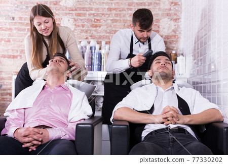 Two men enjoying hairwash by hairdressers Two men enjoying hairwash by hairdressers 77330202