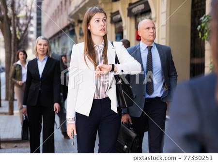 Portrait of hurrying woman among passers 77330251