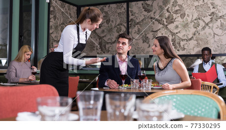 Couple talking with waitress in restaurant 77330295