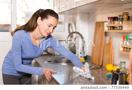 Woman with rag cleaning kitchen 77330449