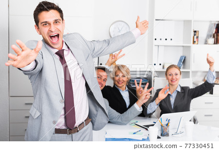 Excited businessman with happy team celebrating victory Excited businessman with happy team celebrating victory 77330451