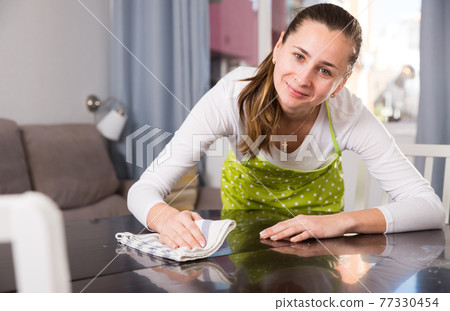 Woman with rag cleaning kitchen table Woman with rag cleaning kitchen table 77330454
