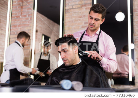 Hairdresser man doing styling of guy with electric hair clipper 77330460