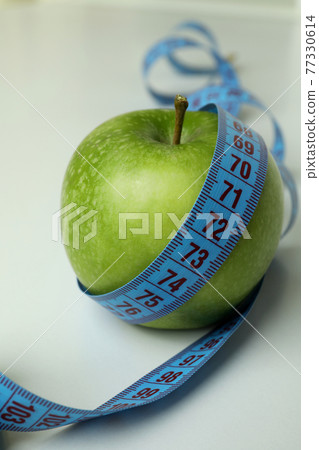 Green apple with measuring tape on white background Green apple with measuring tape on white background 77330614