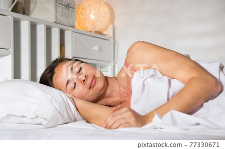 Adult female is sleeping on bed in bedroom at home Adult female is sleeping on bed in bedroom at home 77330671