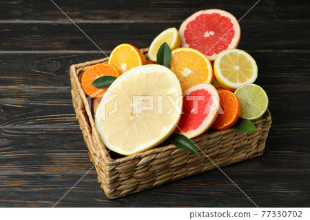 Basket with fresh citrus on wooden table Basket with fresh citrus on wooden table 77330702