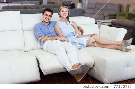 satisfied man and woman are choosing of sofa-transformer in furniture store satisfied man and woman are choosing of sofa-transformer in furniture store 77330785