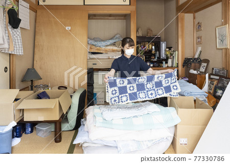 A female worker wearing a mask and cleaning up a messy room A female worker wearing a mask and cleaning up a messy room 77330786