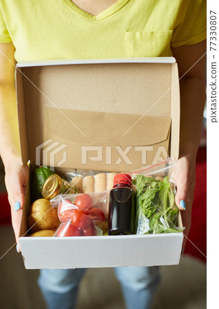 Woman hold in hand food box meal kit of fresh ingredients order from a meal kit company Woman hold in hand food box meal kit of fresh ingredients order from a meal kit company 77330807