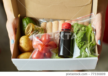 Woman hold in hand food box meal kit of fresh ingredients order from a meal kit company 77330809