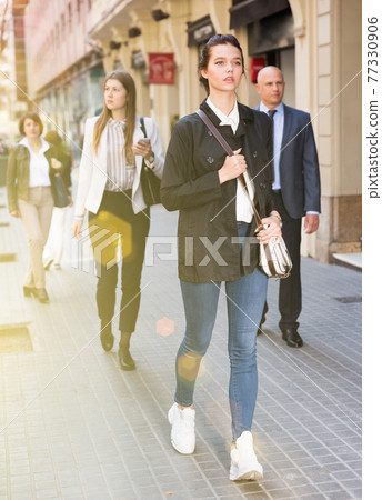 People in formal wear walking down street in city 77330906