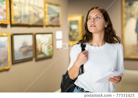 Focused girl visitor, admiring the paintings in the museum 77331025