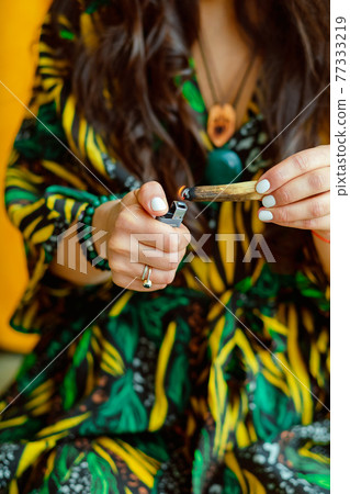A stick of Palo Santo tree in the hands of a girl. A woman lights a stick. Close up. 77333219