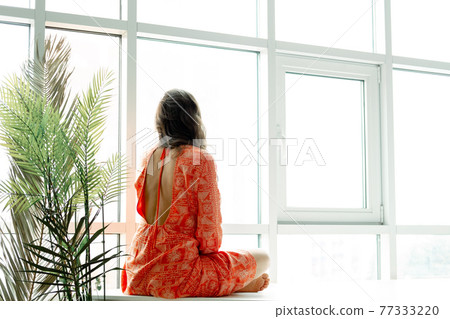 Yoga at home. Keep calm. Attractive young woman sitting on lotus position on floor with eyes closed. 77333220