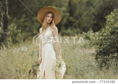 Woman with Flowers in Nature in the Summer. 77334380